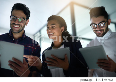Taking care of digital business. Shot of three colleagues using digital tablets while standing together in an office. 120176708