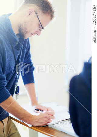 Taking care of those pre-admission papers. Shot of a young doctor filling out paperwork in a hospital. 120177167