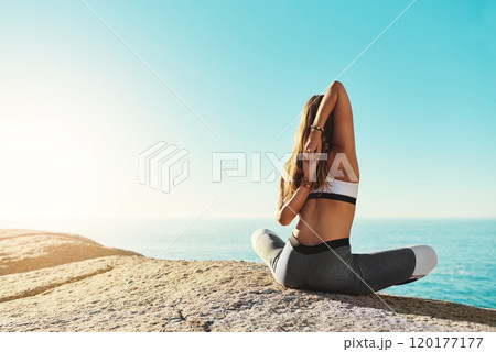 Yoga helps us to reach our goals. Rearview shot of a young woman practicing yoga on the beach. 120177177