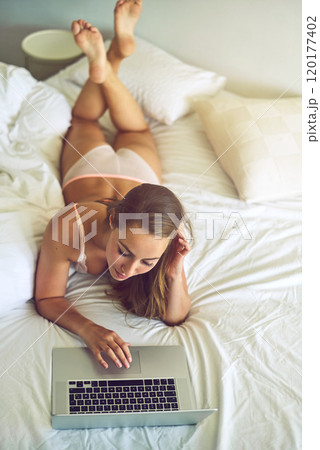 Sexy social networking. Shot of a young woman using a laptop in her underwear during the morning. 120177402