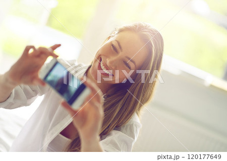 Sunday morning selfies. Shot of a young woman taking a morning selfie in her bedroom. 120177649