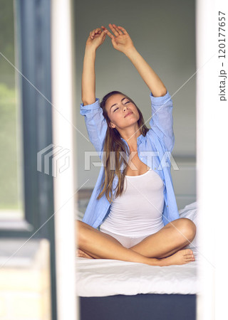 An amazing day begins with an amazing morning. Shot of an attractive young woman stretching in the morning. 120177657