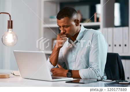 I need to figure this out as soon as possible. Shot of a handsome young businessman looking stressed while working on his laptop during a late night at the office. 120177880