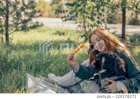 being in nature with pets can reduce stress and improve well-being, red-haired woman, dog in park with ice cream 120178271