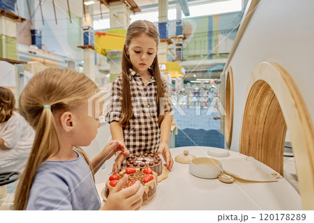 Girls playing chef on playground kitchen Girls playing chef on playground kitchen 120178289