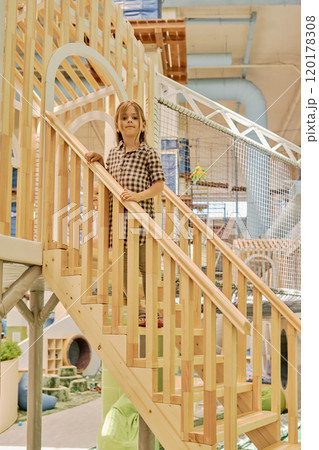 Cute girl standing on wooden staircase 120178308