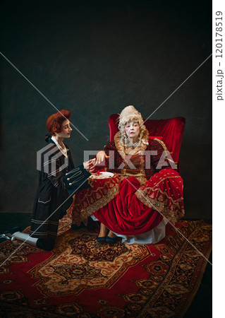 Humorous scene with elderly woman and young man, Medieval empress sitting in chair with young male servant doing painting her nails 120178519