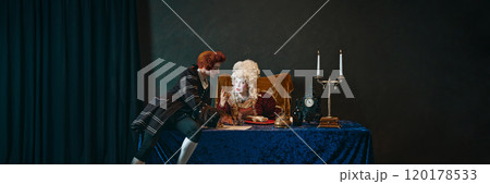 Elderly woman with bright makeup and wig, empress sitting at table and talking to court servant writing a letter. Royal lifestyle. Banner Elderly woman with bright makeup and wig, empress sitting at table and talking to court servant writing a letter. Royal lifestyle. Banner 120178533