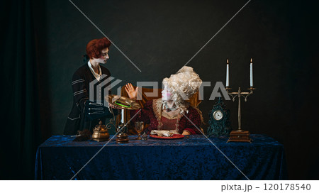 Young man, royal servant serving smartphone to senior woman, empress. Fusion of modernity and classical lifestyle. 120178540