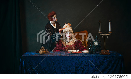 Loyal court favorite brushes wig of elegantly dressed empress, elderly woman sitting at table with serious face. 120178605