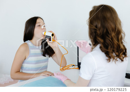 Girl testing breathing function by spirometry in doctors office. Diagnosis of respiratory function in pulmonary disease Girl testing breathing function by spirometry in doctors office. Diagnosis of respiratory function in pulmonary disease 120179225