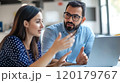 Colleagues having a focused discussion while working together at the office 120179767