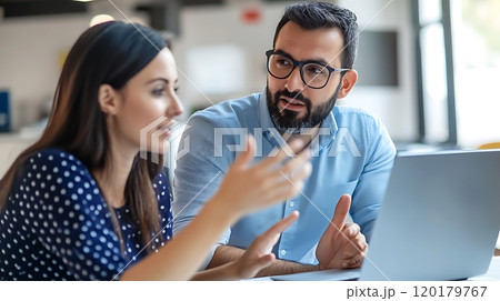 Colleagues having a focused discussion while working together at the office 120179767