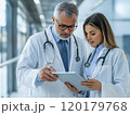 Doctors reviewing patient data on a tablet in a hospital corridor 120179768