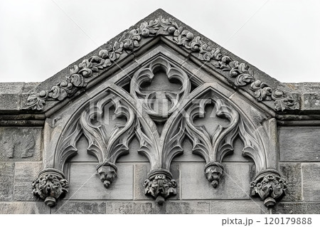 gothic style granite headstone stands majestically arched top displaying intricate stone carvings and sharp motifs clean white background conveying solemn atmosphere. 120179888