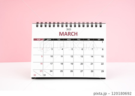 March 2025 desk calendar on white table with pink background. 120180692