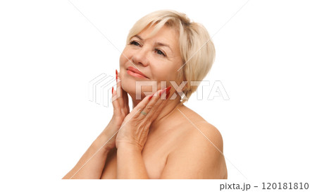 Beautiful Caucasian 60s woman with bared shoulders touching her soft and smooth skin against white studio background. Beautiful Caucasian 60s woman with bared shoulders touching her soft and smooth skin against white studio background. 120181810