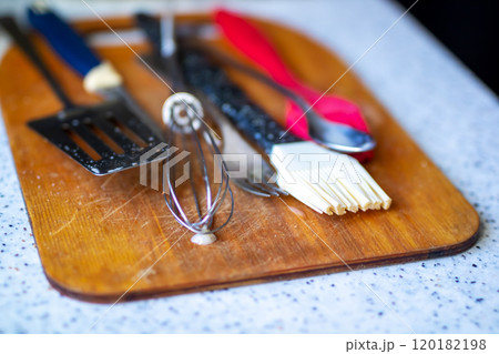 A wooden cutting board with various kitchen utensils on it 120182198