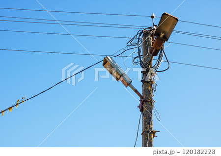 A telephone pole that has a street light fixed and attached to it A telephone pole that has a street light fixed and attached to it 120182228
