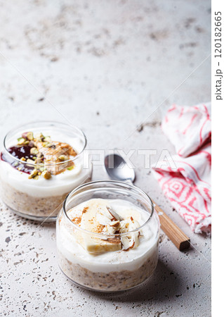 Overnight oatmeal with peanut butter, banana, nuts and jam in jars. 120182665