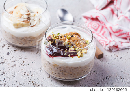 Overnight oatmeal with peanut butter, banana, nuts and jam in jars. 120182666