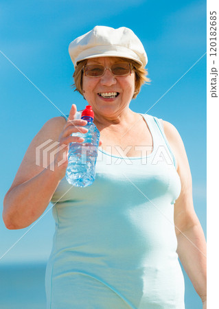old woman drinking mineral water in plastic bottle outdoor 120182685