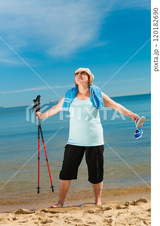 Senior woman practicing nordic walking on beach 120182690