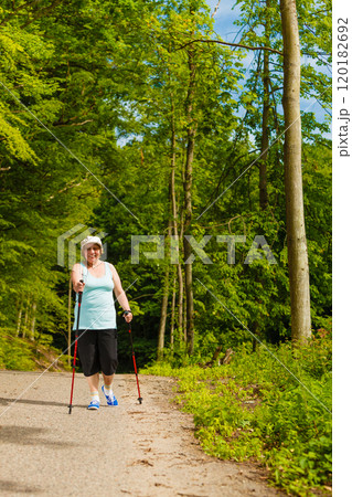 Senior woman practicing nordic walking in park 120182692
