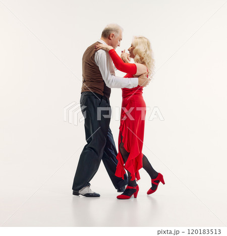 Elderly woman and senior man, elegantly dressed in red dress and black suit, dancing tango with passion isolated on white background Elderly woman and senior man, elegantly dressed in red dress and black suit, dancing tango with passion isolated on white background 120183513