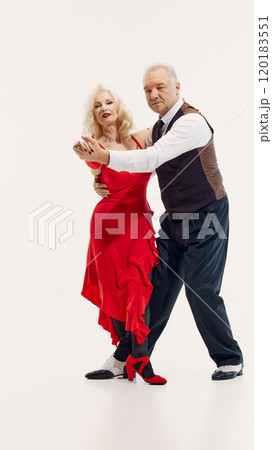 Elegant elderly couple, man and woman dressed in stylish matching dance costumes, dancing tango with passion and energy isolated on white background Elegant elderly couple, man and woman dressed in stylish matching dance costumes, dancing tango with passion and energy isolated on white background 120183551