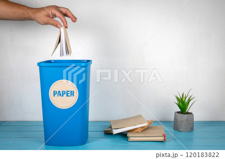 Paper sorting and recycling. Man's hand throws a book in a blue trash can 120183822