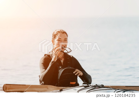Kayaking Woman Paddle Sea - Woman in kayaking gear sits on a dock preparing to kayak on the water. Kayaking Woman Paddle Sea - Woman in kayaking gear sits on a dock preparing to kayak on the water. 120184235