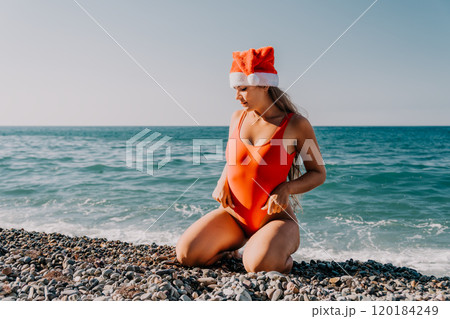 Woman in Red Swimsuit with Santa Hat on Beach 120184249