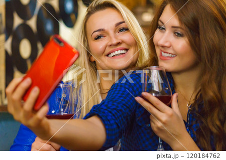 Girls in pub club taking self photo with phone 120184762