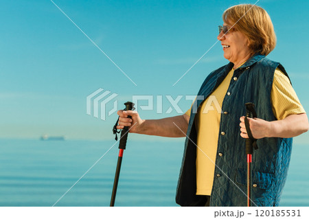Senior woman practicing nordic walking on beach Senior woman practicing nordic walking on beach 120185531