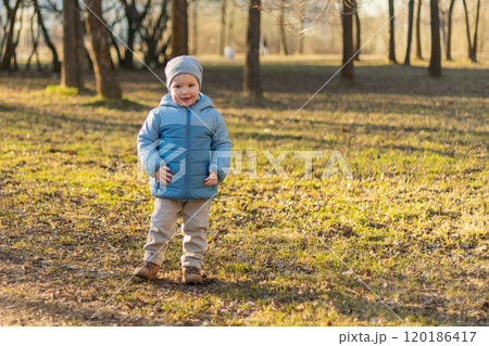 Happy baby child outdoor. Little toddler boy having fun on walk in park. Baby son smiling playing outdoor. Little child resting walking in nature. Little toddler child having fun on walk 120186417