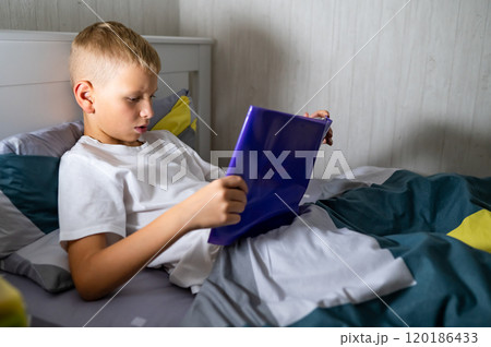 fair-haired teenage boy reading a book before bed fair-haired teenage boy reading a book before bed 120186433