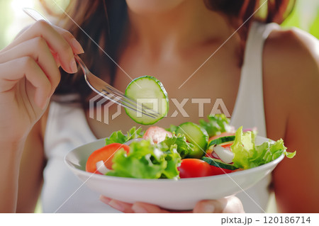 Woman eating salad with fork close-up, healthy eating concept 120186714