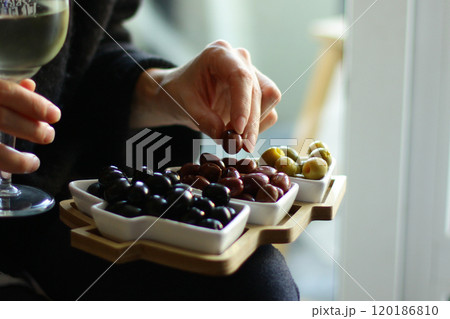 Christmas and New Year snacks. Hands holding a plate in the shape of a Christmas tree with olives. 120186810