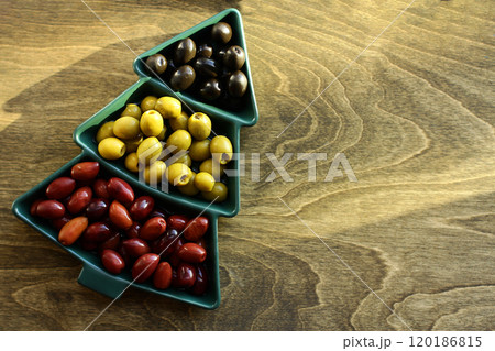Green, black and red olives in a vase in the shape of a Christmas tree on a wooden background Green, black and red olives in a vase in the shape of a Christmas tree on a wooden background 120186815