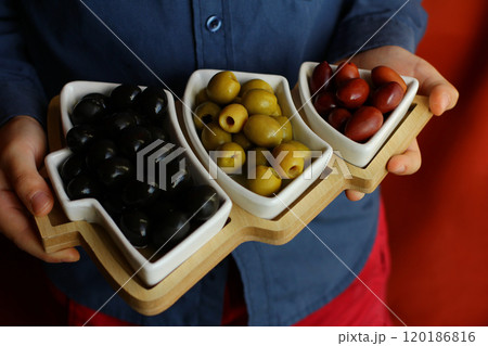 Christmas and New Year snacks. Hands holding a plate in the shape of a Christmas tree with olives. Christmas and New Year snacks. Hands holding a plate in the shape of a Christmas tree with olives. 120186816