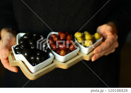 Christmas and New Year snacks. Green, black and red olives in a herringbone-shaped plate 120186826
