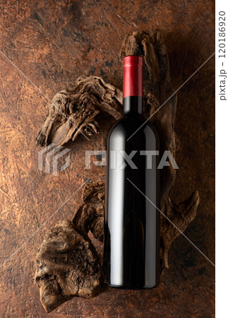 Bottle of red wine and old weathered snags on a brown vintage background. Bottle of red wine and old weathered snags on a brown vintage background. 120186920