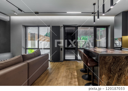 Modern luxury apartment with a free layout in a loft style in gray and dark colors. Stylish kitchen area with an island, marble countertop Modern luxury apartment with a free layout in a loft style in gray and dark colors. Stylish kitchen area with an island, marble countertop 120187033