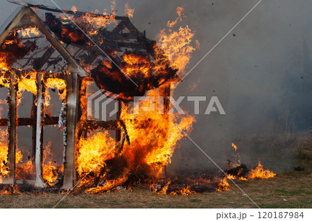burning fire in a small wooden house in the village 120187984