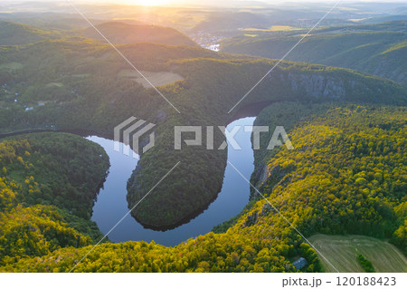 As the sun sets, the Vltava River reflects vibrant hues and encircles lush green hills in Czechia, creating a breathtaking view that captures the beauty of nature at dusk. As the sun sets, the Vltava River reflects vibrant hues and encircles lush green hills in Czechia, creating a breathtaking view that captures the beauty of nature at dusk. 120188423