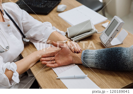 Doctor examining patients pulse and health data at medical consultation Doctor examining patients pulse and health data at medical consultation 120189041