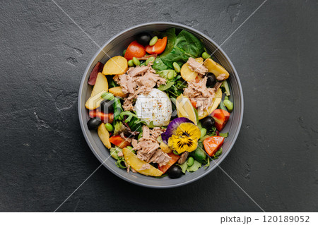 Gourmet salad bowl with tuna, poached egg, colorful vegetables, and edible flower garnish Gourmet salad bowl with tuna, poached egg, colorful vegetables, and edible flower garnish 120189052