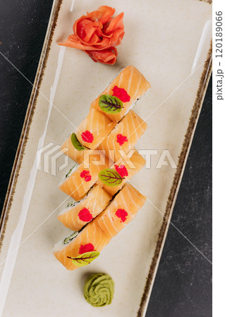 Close-up of sushi rolls with salmon, cream cheese, and cucumber, garnished with wasabi and roe Close-up of sushi rolls with salmon, cream cheese, and cucumber, garnished with wasabi and roe 120189066