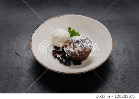 Decadent chocolate lava cake with vanilla ice cream, berries, and mint on a rustic plate 120189073